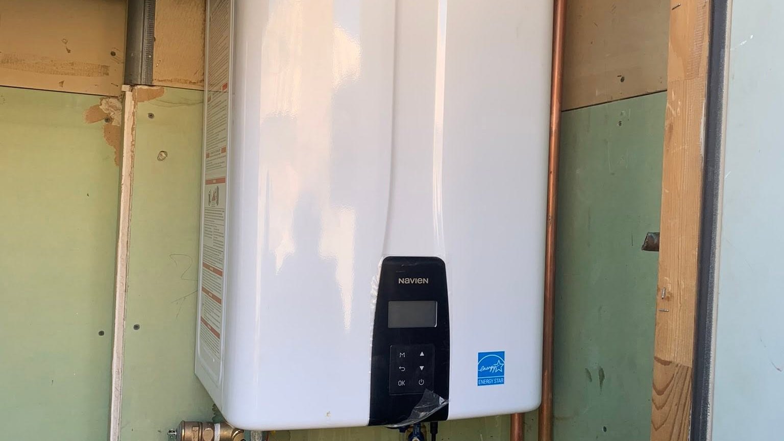 Wall-mounted tankless water heater with connected copper and PVC piping